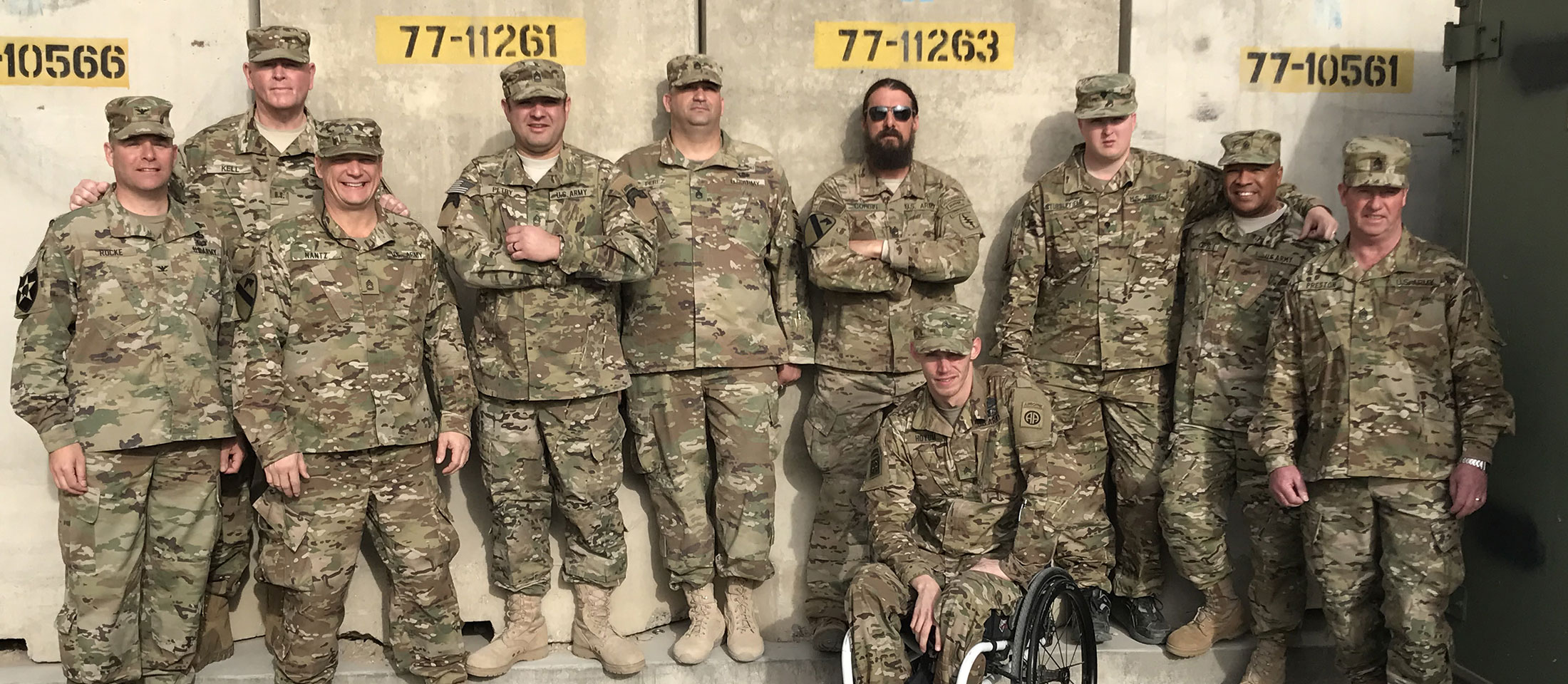 Military servicemen wearing camo and standing posed for a group photo. 